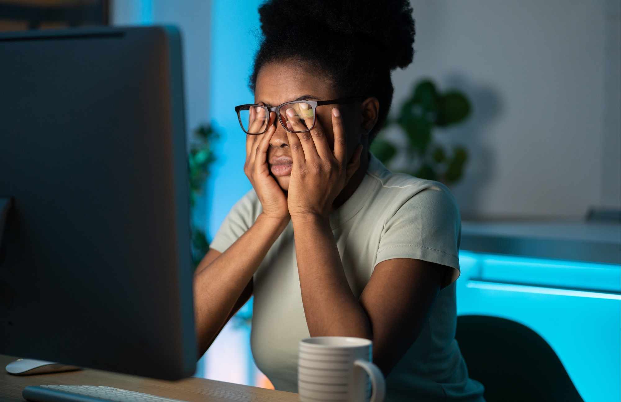 Tired woman rubbing her eyes while working late, symbolizing fatigue and low energy caused by hormonal imbalances.