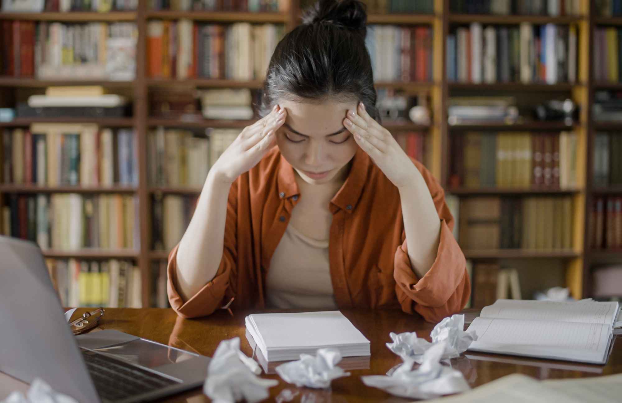 Young woman holding her head in frustration, struggling with focus and brain fog due to hormonal imbalances.