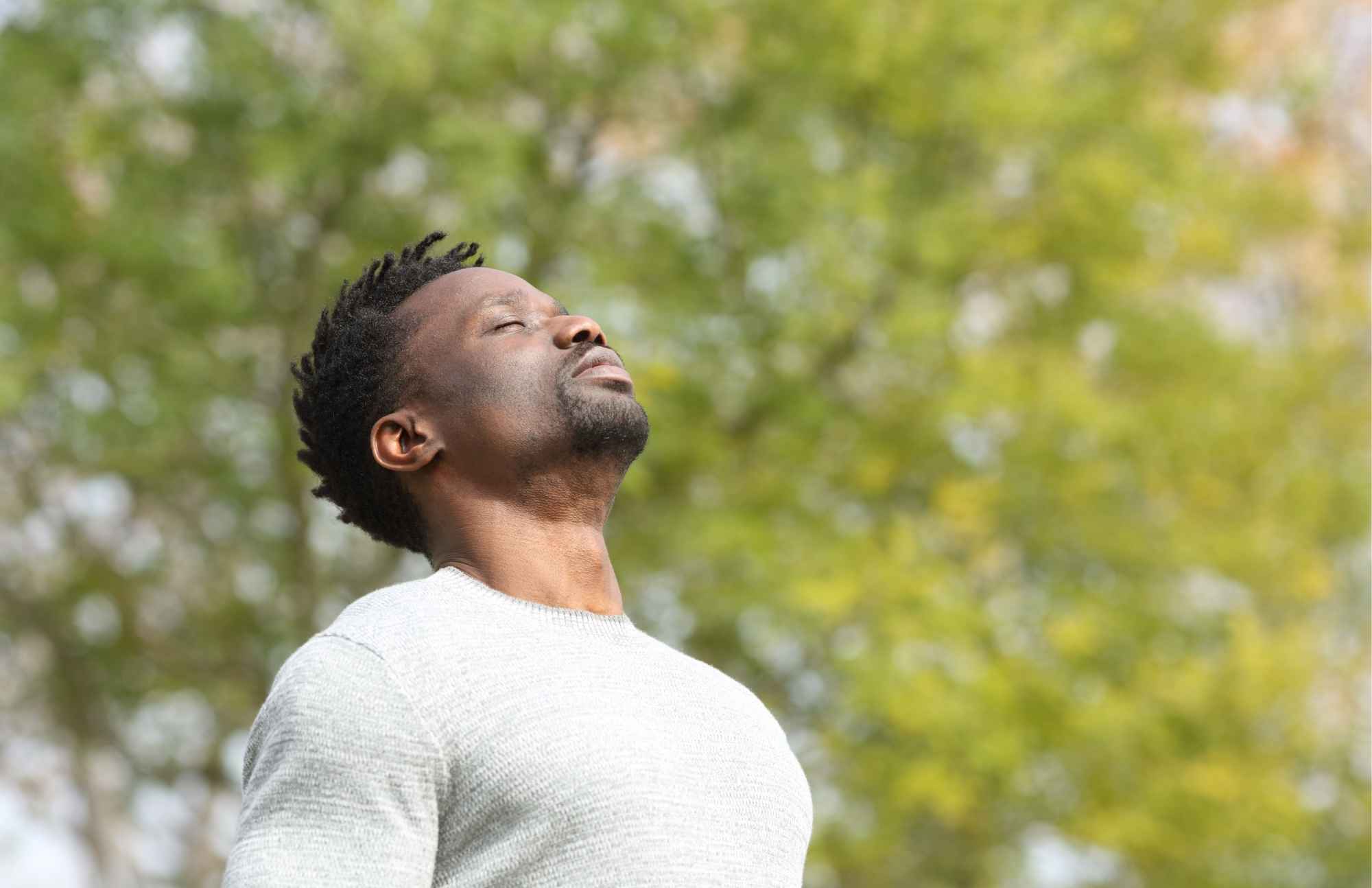 A man standing outside with his eyes closed, soaking in the sunlight, representing the importance of Vitamin D for overall health.