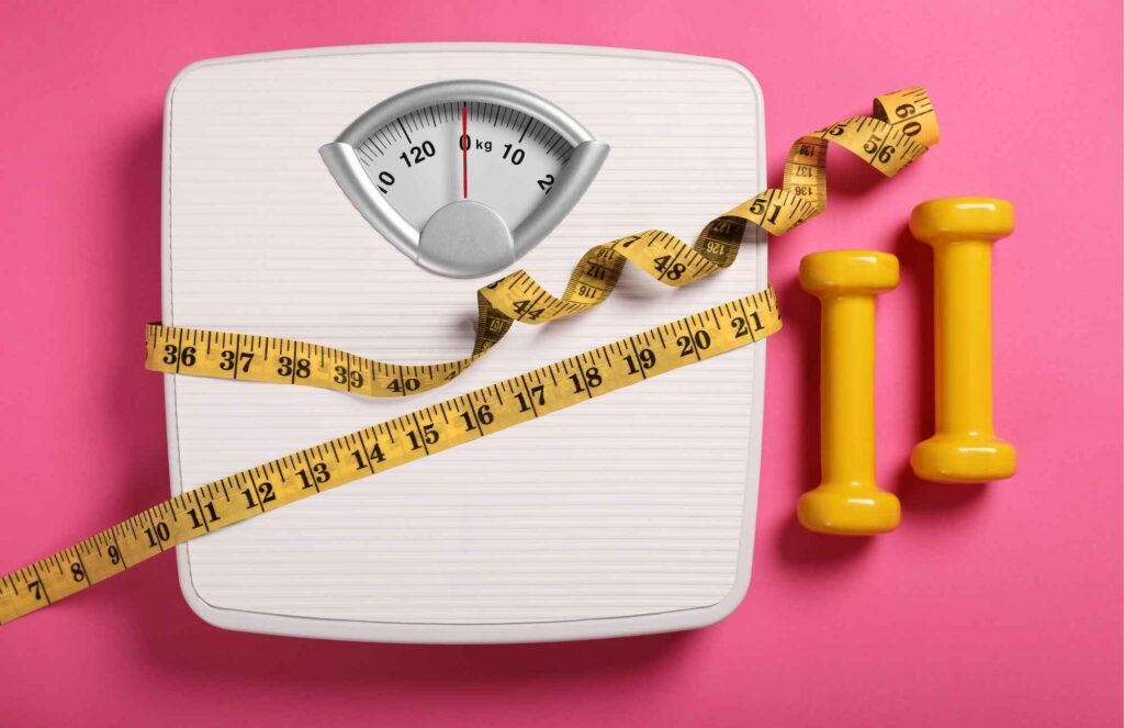 Weight scale and dumbbells symbolizing weight gain and metabolism changes that can be helped through menopause treatment