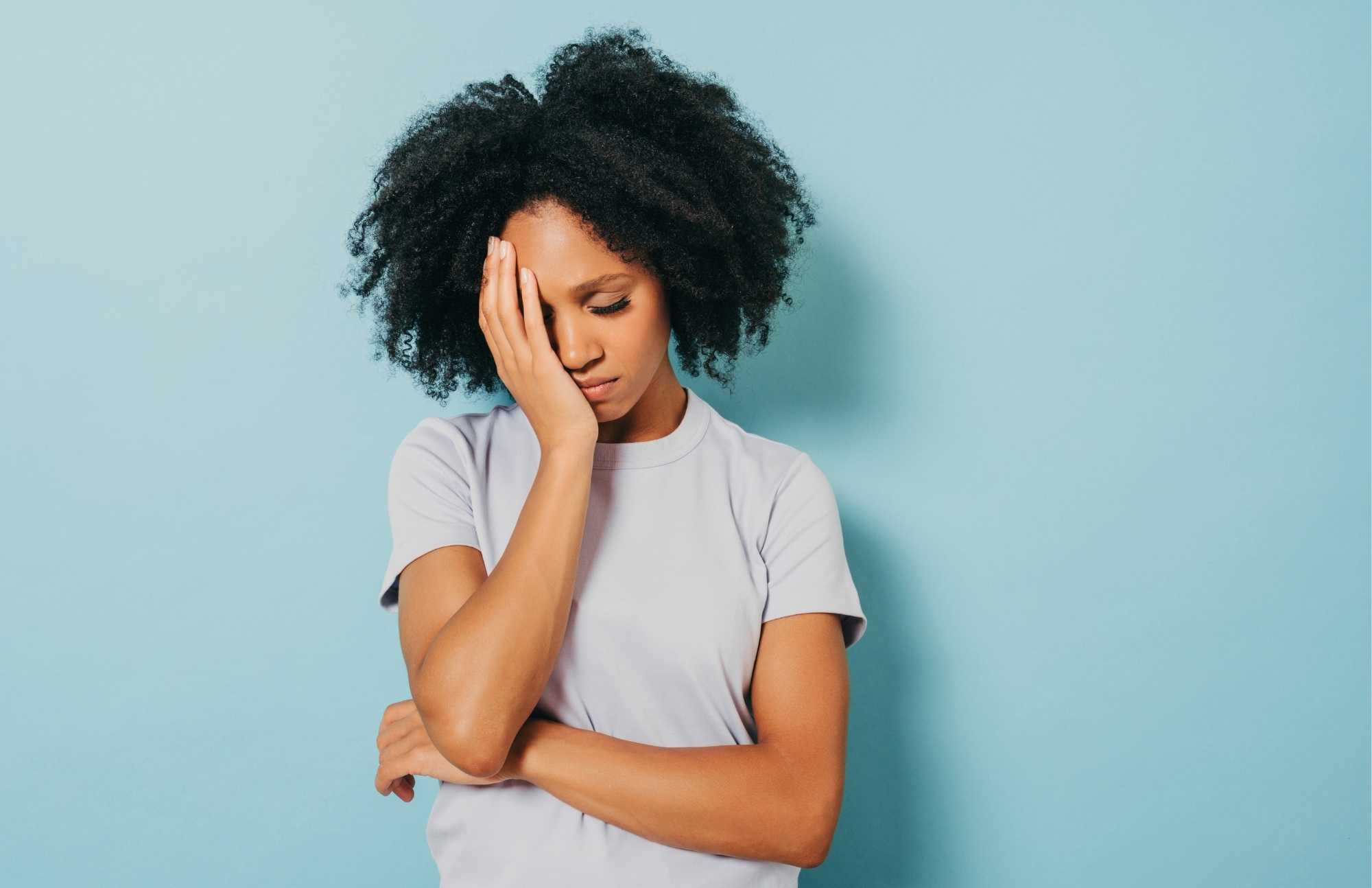 A woman with a pained expression holding her forehead, symbolizing relief from inflammation-related discomfort.